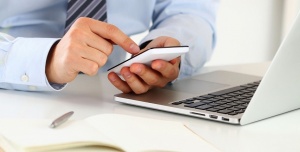 66204538 - businessman hands typing something on smart phone sitting at his office. close up view. mobile applications, communicating, playing games, social media, organizing work or wireless technology concept.